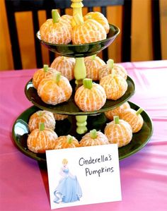 three tiered trays filled with oranges on top of a pink table cloth