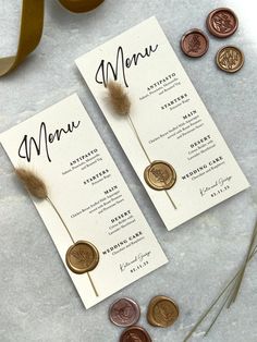 two wedding menus with coins and ribbons on the table next to eachother