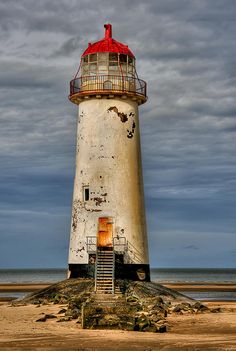 an old lighthouse on the beach with stairs leading up to it