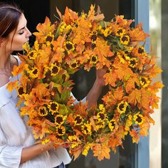 a woman holding a wreath with sunflowers on it