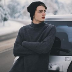 a young man leaning on the hood of a car