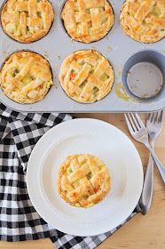 a muffin tin filled with mini pies on top of a wooden table next to a white plate