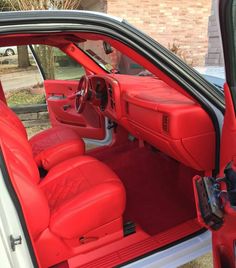 the interior of a red and white car with its door open to show the driver's seat