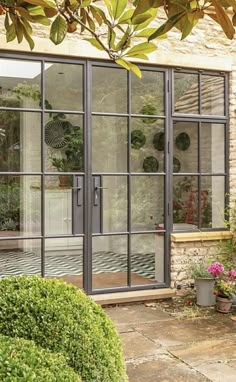 an outside view of a house with glass doors and potted plants in the front yard