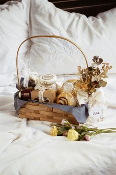 a basket filled with lots of different types of items on top of a white bed