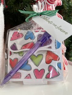 a christmas ornament and pen in a package on a table next to a candy cane