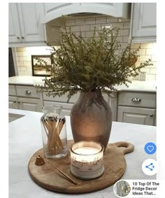 a vase filled with flowers sitting on top of a wooden tray next to a candle