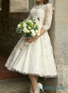 a woman in a wedding dress leaning against a wall