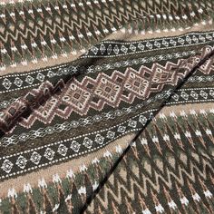 closeup of the pattern on an afghan shawl in brown, green and white colors