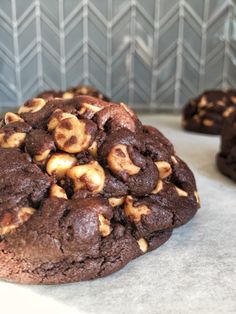 a chocolate cookie with nuts on it sitting on a counter top next to other cookies