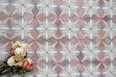 some flowers are sitting on the floor in front of a mosaic wall with pink and white tiles