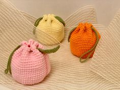 three crocheted bags sitting on top of a white surface