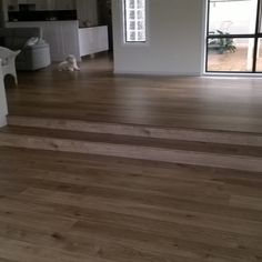 an empty living room with wood floors and white furniture in the background, looking out to open patio doors