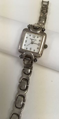 Watch made by Sinclair with a sterling silver case and heavy bracelet band.  Quartz movement.  Small sapphire stones on the pin ends of the case.  Bracelet measures 6 1/2" long and 8 mm wide.  Links are 3 mm thick.  The case measures 3/4" x 3/4". Fold over clasp. Preowned in good condition. Silver Rectangular Jewelry And Watches For Anniversary, Rectangular Silver Metal Watch, Silver Rectangular Metal Watch, Classic Silver Metal Jewelry And Watches, Vintage Jewelry Antique, Sapphire Stones, Jewelry Antique, Sapphire Stone, Pretty Jewellery