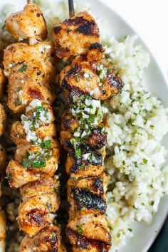 chicken kabobs on skewers with white rice and garnishes