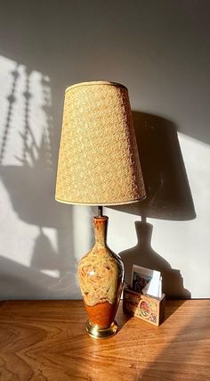 a lamp sitting on top of a wooden table next to a shadow cast by a wall