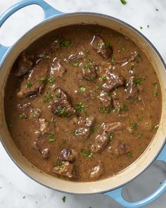 a blue pot filled with meat and mushrooms