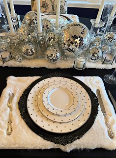 a black and white table setting with disco ball centerpieces, silverware and candles