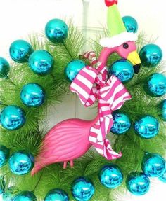 a flamingo wreath with blue ornaments and a party hat on it's head