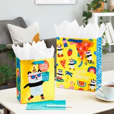 two colorful bags sitting on top of a table next to a cup and saucer