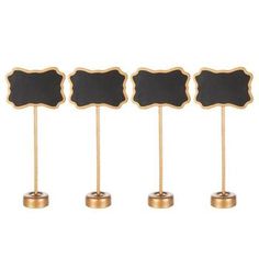 four black and gold place cards with chalkboards on stands in front of a white background