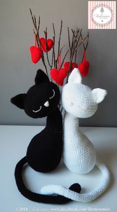 two crocheted black and white cats sitting next to each other with hearts on their heads