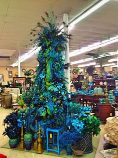 a christmas tree in a store filled with lots of blue and green decorations on display