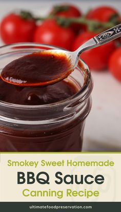 a spoon full of bbq sauce sitting in a jar with tomatoes on the side