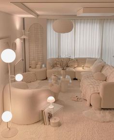 a living room filled with lots of white furniture and lights on the wall above them