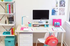 a white desk topped with a computer monitor next to a book shelf filled with books