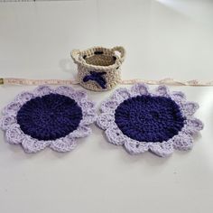 two crocheted flower coasters next to a measuring tape