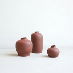 three brown vases sitting next to each other on a table