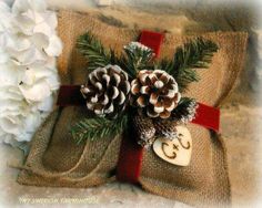 two pine cones are wrapped in burlock and tied with red ribbon, sitting on a pillow