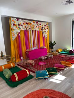 a room decorated in bright colors with lots of pillows and rugs on the floor