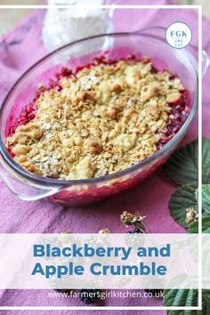 blackberry and apple crumble in a glass bowl on a purple tablecloth with green leaves