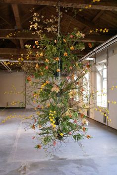 an arrangement of flowers is suspended from the ceiling in a large room with exposed ceilings