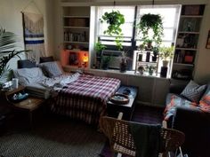 a living room filled with furniture next to a window covered in plants and bookshelves