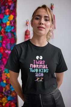 I Was Normal Two Kids Ago" is a humorous and relatable t-shirt perfect for moms who want to express the changes that motherhood brings. This unisex shirt is a great Christmas gift for moms, new moms, or anyone with a sense of humor. Made from high-quality materials, this shirt is soft, loose-fitting, and comfortable, making it a favorite for everyday wear. The design is both funny and cute, making it a great conversation starter and a fun addition to any wardrobe. Whether it's for yourself or as Funny Black T-shirt For Mother's Day, Funny Graphic Print T-shirt For Mother's Day, Funny Pre-shrunk Tops For Mother's Day, Funny Text Print T-shirt For Mother's Day, Funny Short Sleeve T-shirt For Mother's Day, Funny Mother's Day Graphic Print T-shirt, Funny Mother's Day Graphic T-shirt, Playful Crew Neck T-shirt With Funny Text, Mother's Day Black T-shirt With Funny Print