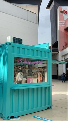 a large blue container sitting on the side of a road next to a tall building