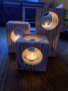 three wooden blocks with lit candles in them