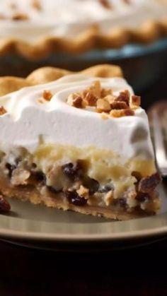 a slice of pie with whipped cream and pecans on top sits on a plate