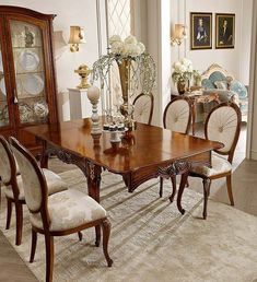 a dining room table with chairs and a china cabinet in the corner next to it