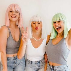 three women with pink and green hair standing next to each other, making the peace sign