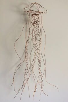 a wire sculpture hanging from the side of a wall