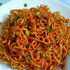 noodles with meat and green onions on a white plate