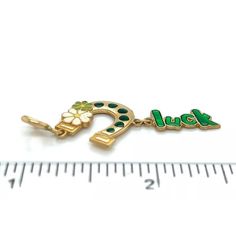 This adorable charm or pendant is crafted from 14k yellow gold featuring a horse shoe with green enamel dots and two flowers decor, one in white enamel and the other green enamel. Dangling from the horse shoe is a small charm with the word spelled "luck" in green enamel. The bail is a round spring ring clasp.  Material:  14k yellow gold Hallmark: 14k Measurement:  1.69" long x 0.69" wide Weight:  1.7 grams Good Luck Yellow Gold Charms Jewelry, Antique Good Luck Charms Jewelry, Vintage Good Luck Charms Necklace, Good Luck Horseshoe Charms Jewelry, Silver Horseshoe Charms Jewelry, Irish Style, Small Charms, Green Enamel, Gold Enamel