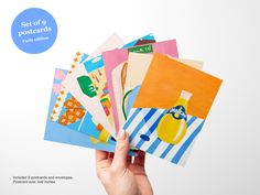 a hand holding up several different colored postcards with the caption set of 9 postcards