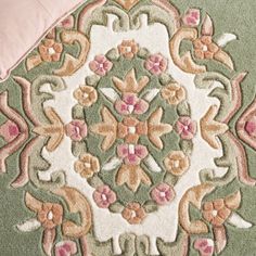 a close up of a rug on the floor with pink and green flowers in it