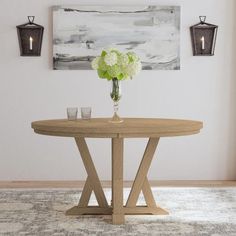 a vase with flowers on top of a table in front of two wall sconces