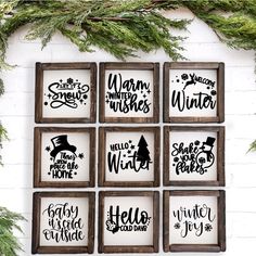 six wooden frames with christmas sayings hanging on the wall next to evergreen branches and pine cones